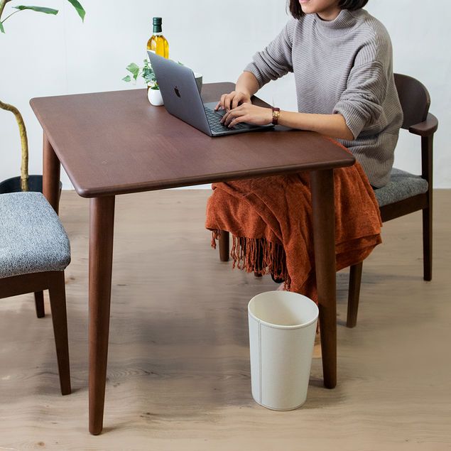 ヒーター付きのダイニングテーブルに椅子をコーディネートした部屋でパソコンに向かう人