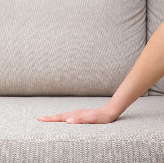 一人暮らしのソファの座り心地を確かめる人の手