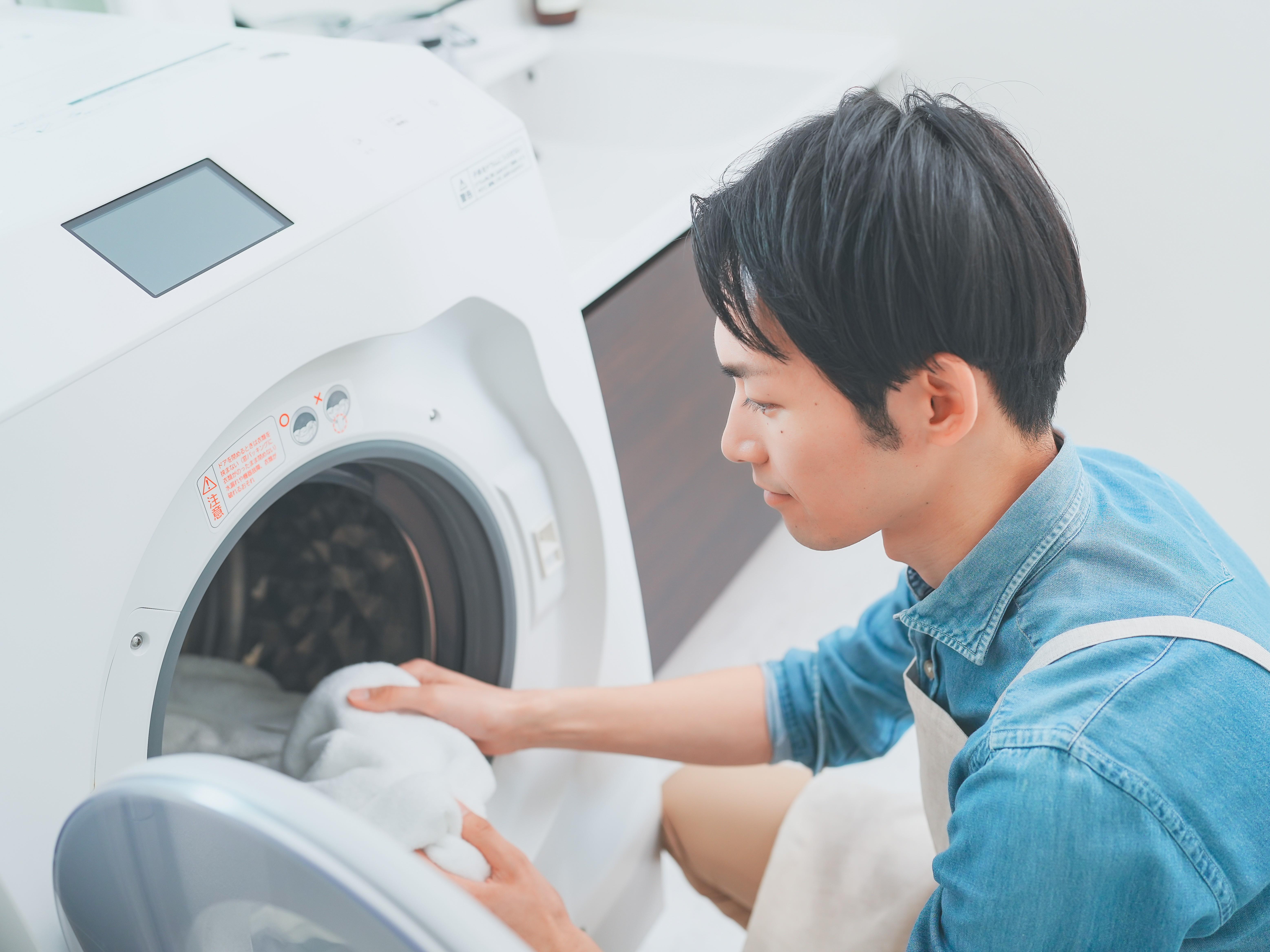プロによる徹底洗浄でいつでも清潔な洗濯機を使う男性