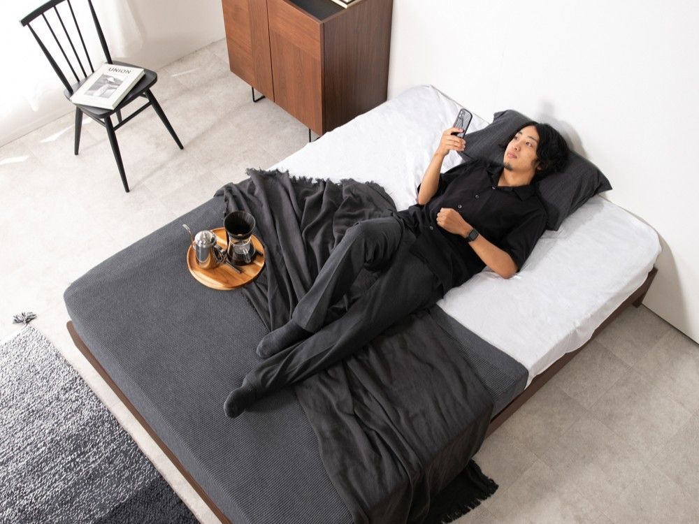家で毎日眠ってて試せる家具と家電のレンタル・サブスククラスで借りたベッドに寝る男性