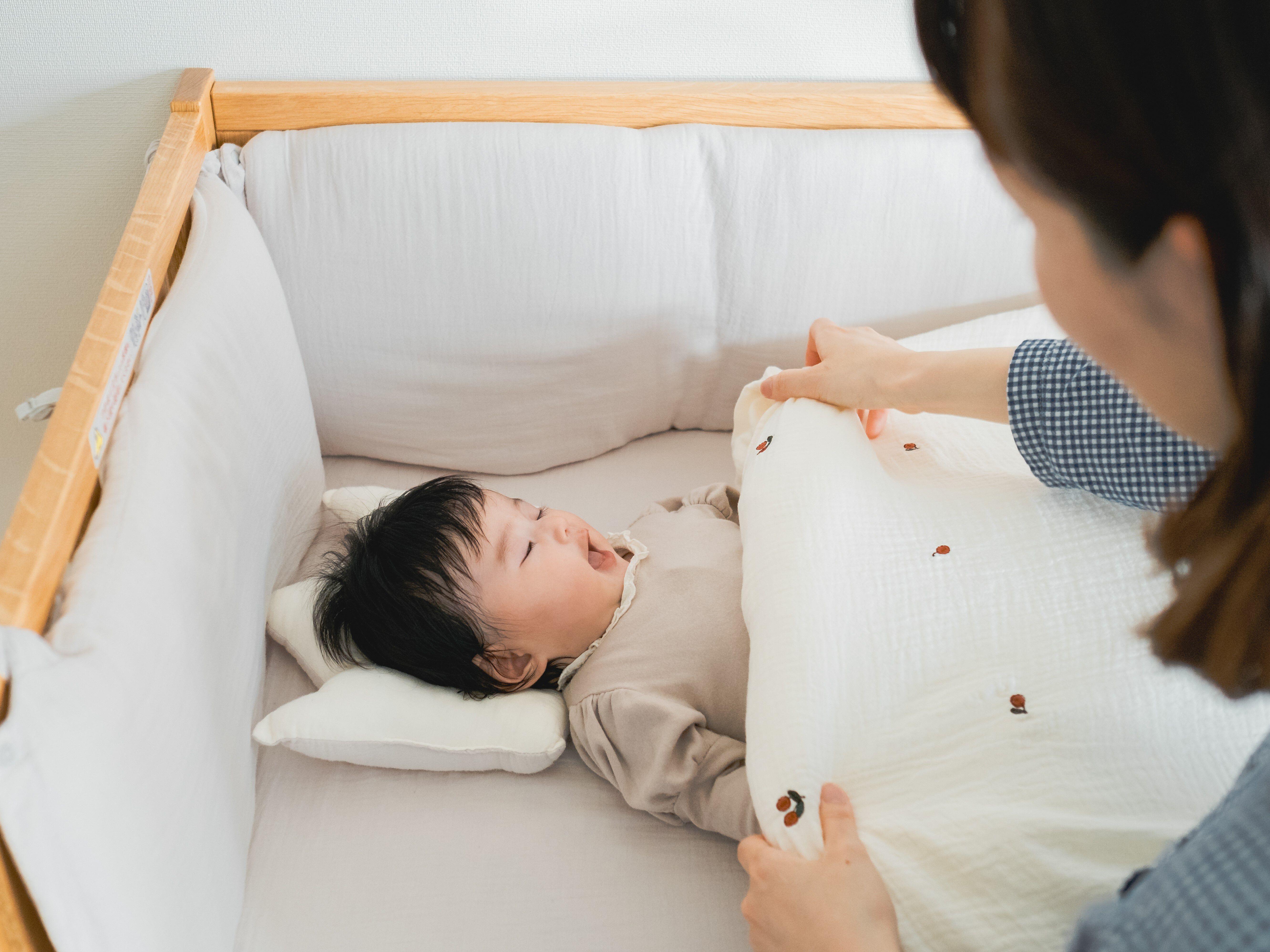 ベビー布団をかけるママ