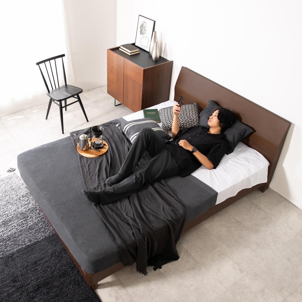 ダブルサイズのベッドでくつろぐ男性