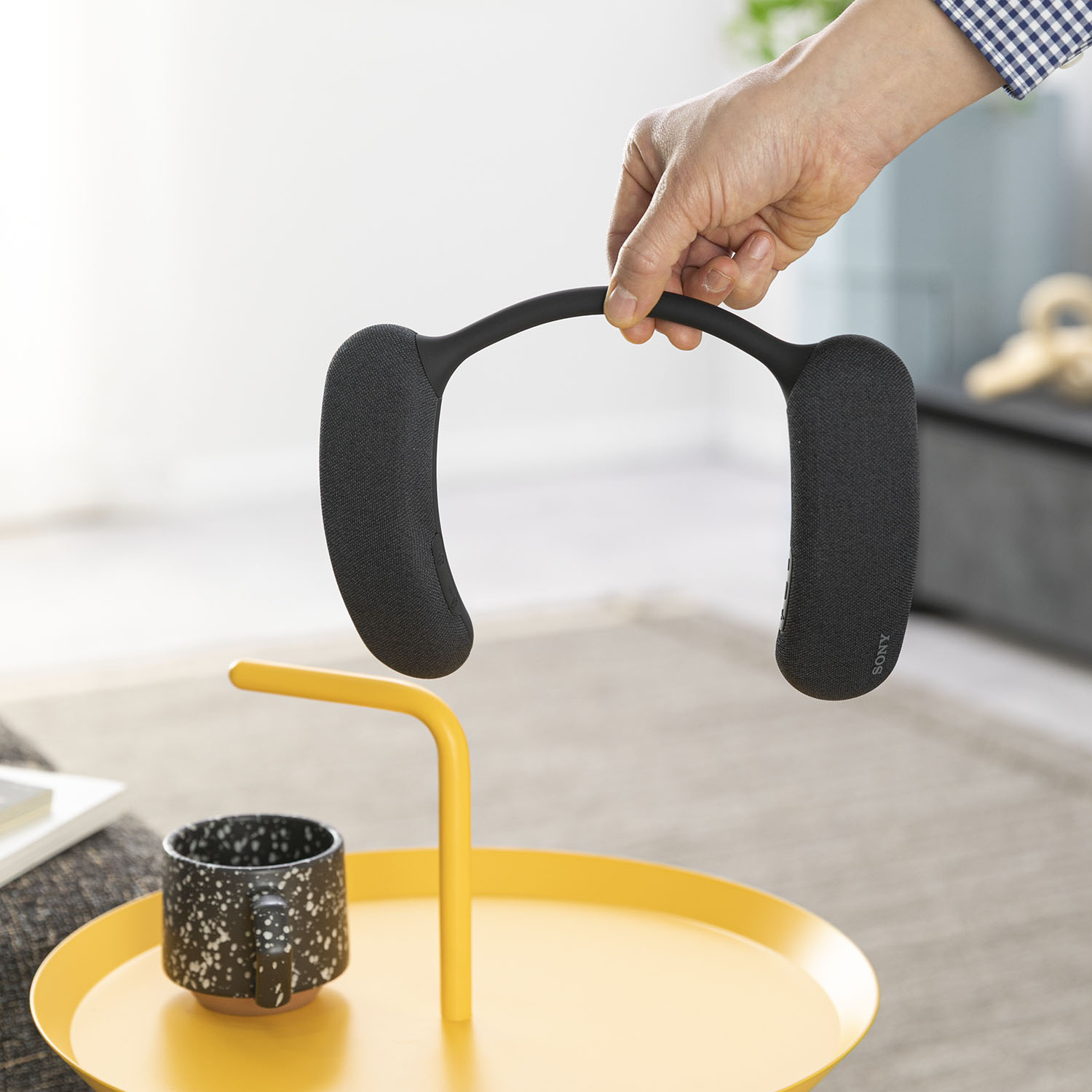 家電のレンタル・サブスククラスでほかのテレビ用スピーカーもレンタルして試している男性の手とSONY（ソニー） ワイヤレスネックバンドスピーカー