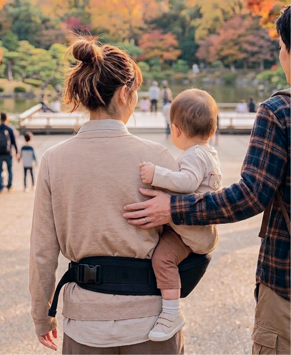 紅葉の公園で子どもを抱っこして歩く家族