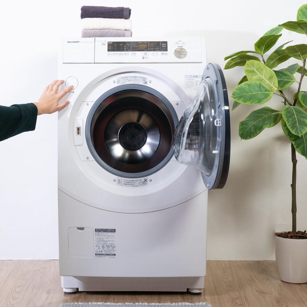 ドラム式洗濯機のスイッチを押そうとする人